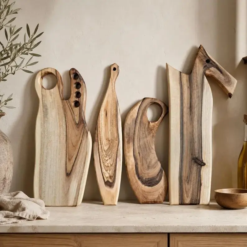 Rustic handmade wooden chopping boards layered upright against a kitchen backsplash.